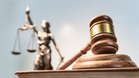 im Vordergrund ein Richterhammer im Hintergrund eine Justitia zu sehen im Vordergrund ein Richterhammer im Hintergrund eine Justitia zu sehen